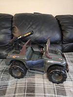 Side view of vintage G.I. Joe Rhino Jeep showing open doors, large tires, and mounted cannon.