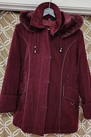 Front view of a burgundy women's winter jacket featuring a faux fur lined hood and detailed stitching.