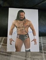 Clear image of a signed 8x10 photo of WWE wrestler Drew McIntyre showing full body and signature in black marker on the front.