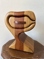 Front side view of the handcrafted wooden box showing the curved design and banded wood pattern.