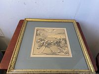 Overall view of framed foxhounds print showing gold frame and double matting on wood table.