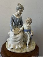 Front view of porcelain figurine showing mother reading with son standing.