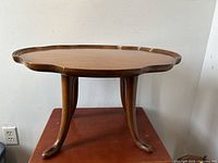 Front view of the polished walnut table showing the splay leg design and scalloped edge top