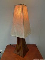 Photo of lamp turned off showing fabric shade and wooden flared base with minor chip.