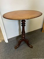 Full view of Georgian style mahogany pedestal wine table, circular top, three curved legs
