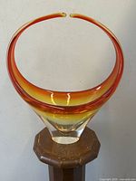 Front view of signed Chalet art glass vase on wooden pedestal