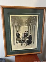 Framed signed print viewed straight on, showing the surreal wedding scene with five figures beneath stylized leafless trees in winter snow.