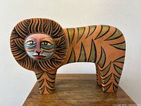 Front angled view of wooden lion sculpture highlighting painted face and body details.