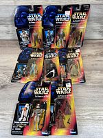Seven new Star Wars The Power of the Force action figures displayed in original packaging, featuring various characters including Stormtroopers, Jawas, and other figures with accessories visible through blister packs.