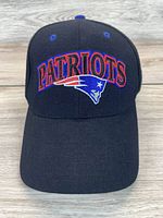 Front view of navy blue vintage fitted hat with New England Patriots logo embroidered on front with red and white accents.