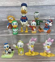 Photo showing all 10 vintage Disney PVC toy figures arranged on a clear stand for display.