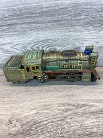 Side view of vintage tin toy train showing detailed lithograph design and smokestack