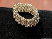 Close-up photo of Birks sterling silver women's ring showing the woven chainmail style band design on a black background.