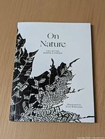 Front cover showing the title 'On Nature: Collected Works & Poems' with a detailed black leaf illustration, softcover book on a wooden surface.