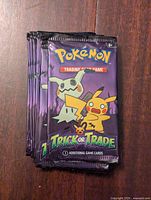 Stack of 12 sealed Pokemon Trick or Trade trading card packs showing front design with Pikachu and Mimikyu artwork.