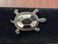 Front view of turtle pin brooch showing marcasite stones and mother-of-pearl inlay.
