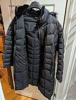 Full view of open black women's winter coat showing interior and sleeves.