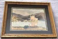 Front view of the framed watercolour depicting Eilean Donan Castle and Loch Duich with surrounding landscape and bridge, showing signature and matting.