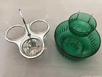 Photo of two serving dishes on a flat surface, showing green cut glass bowls and three glass dip dishes on chrome stand with spoons.