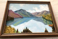 Full view of the Scottish folk art oil painting showing fabric overlays forming mountains and water reflections in a brown wooden frame.