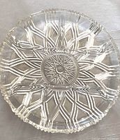 Raised glass dish featuring a star pattern in the base and a notched edge.