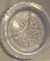 Smallest clear glass serving dish showing 3 compartments with peach, pear, and raspberry embossed designs and raised dots on edge