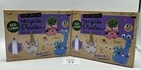 Two unopened Create Your Own Recycle Planter Eco Craft kits, each featuring decorative animal-shaped planter bases and assembly/painting supplies