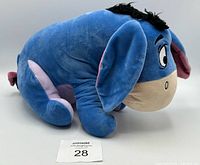 Side view of blue Eeyore plush showing body shape, tail and tag.