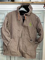Brown Dri-Duck jacket with hood, front zipper, pockets, and John Deere logo on chest.