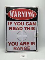 Front view of the metal warning sign featuring the message and target crosshair graphic.