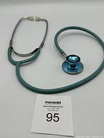 Full view of stethoscope showing green tubing, metal chest piece, and white ear tips