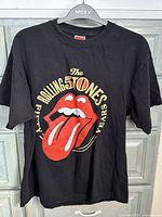 Front view of black T-shirt with The Rolling Stones 50 Years logo and red tongue and lips graphic.