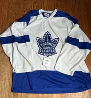 Full view of the white and blue Toronto Maple Leafs hockey jersey with stain on sleeve