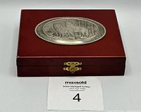Closed wooden box with dark finish and an oval silver-toned plaque showing three wolves standing in a natural setting.