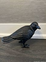 Front side view of the black iron bird sculpture showing detailed wing and head features.