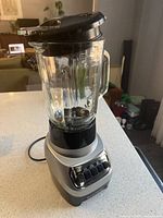 Black+Decker glass blender on a kitchen countertop, showing full view of blender with lid and glass jar.