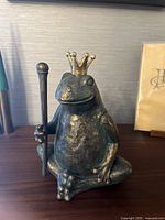 Front view of the frog sculpture showing the full body, crown, and scepter