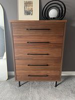 Front view of the Structube tall chest of drawers with 5 drawers and metal handles, showing walnut finish and minor repaired damage on the top surface.