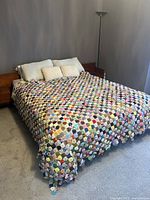Full view of the handmade vintage antique yo-yo quilt spread over a queen size bed in a minimalist bedroom setting.