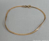 Full view of the 10K yellow gold bracelet laid flat showing length and chain style.