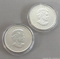 Obverse side showing Queen Elizabeth II profile, denomination 5 dollars, and year 2011 on two silver coins in protective capsules.