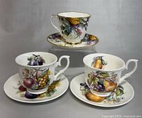 Three English Duchess bone china teacups and matching saucers displayed showing front views of the detailed fruit and floral patterns and gold trim.