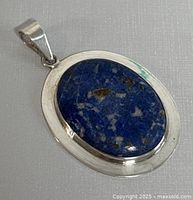 Front view of oval lapis lazuli stone set in polished sterling silver pendant.