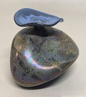 Side view showing rounded base, subtle colorful iridescent finish with speckled patterns and organic shape.