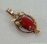 Front view of pendant showing openwork gold frame and coral cabochon