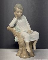 Front and side view of the Lladro figurine showing the boy sitting on tree stump holding a book.