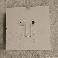 Top view of the white AirPods 3rd Generation box, shows signs of wear and tape marks, image used to identify packaging and set context.