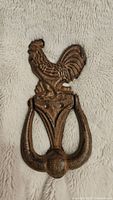 Front view of the cast iron rooster door knocker showing detailed rooster figure and knocker handle.