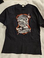 Front view of black Harley Davidson T-shirt size XL with eagle holding American flag graphic inside orange shield and 'Harley-Davidson' text