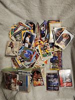 Photo of a large mix of loose and bundled sports cards on a beige fabric background showing various players from baseball and basketball.